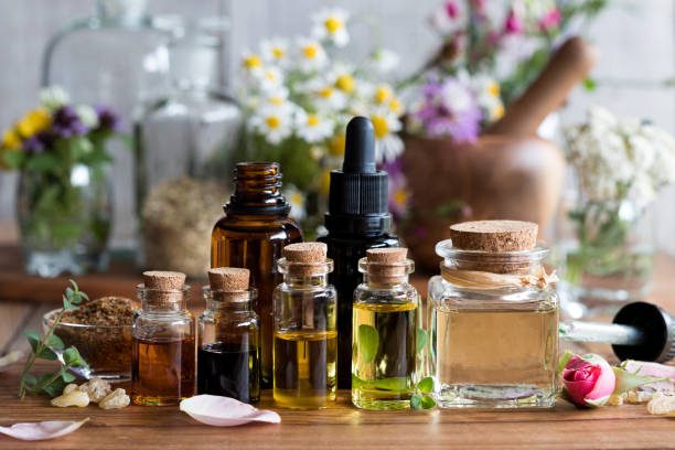 Selection of essential oils with various herbs and flowers in the background Selection of essential oils with various herbs and flowers in the background
